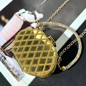 Detailansicht einer luxuriösen goldenen Abendtasche mit funkelndem Strassgriff und Kette.