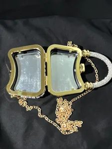 Detaillierte Ansicht der goldenen Abendtasche mit Strassgriff und Metallkette.