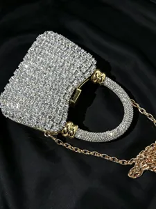 Nahaufnahme der glitzernden Strass-Abendtasche mit rundem Griff und goldener Kette.