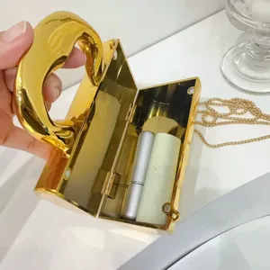 Nahaufnahme der goldenen Metall-Abendtasche mit strukturierter Box-Form und Details.
