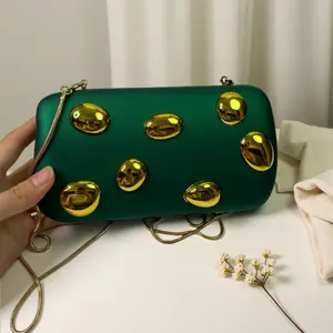 Detailansicht der dunkelgrünen Clutch Tasche mit glänzenden goldenen Nieten und Kette.