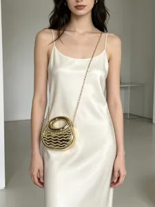 Detailaufnahme einer glamourösen goldenen Strass-Acryl-Abendtasche mit Kette am Kleid.