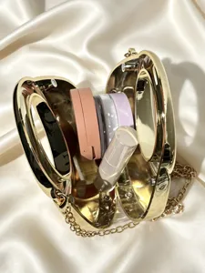 Detailansicht einer luxuriösen goldenen Metall-Abendtasche mit Kette und Kosmetikartikeln im Inneren.