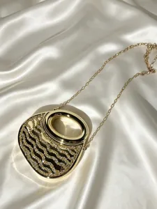 Nahaufnahme der goldenen Abendtasche mit Strasswellenmuster und edler Metallkettentasche.