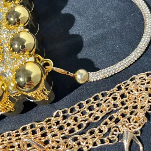 Detailed view of luxury gold rhinestone evening bag featuring shiny metal spheres and chain.