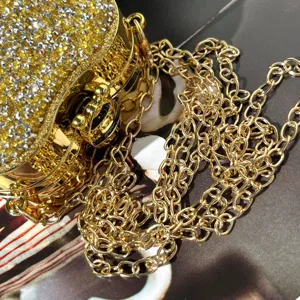 Nahaufnahme einer luxuriösen goldenen Strass-Abendtasche mit metallischem Kettenriemen.
