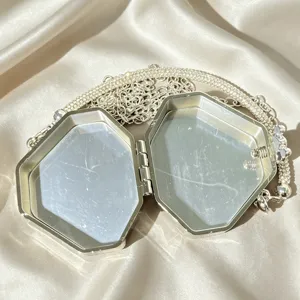 Hexagonal evening clutch bag detail view showcasing open interior and sparkly rhinestone chain.