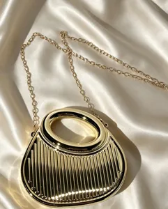 Detailaufnahme einer luxuriösen goldenen Metall-Abendtasche mit rundem Griff und Kettengurt.