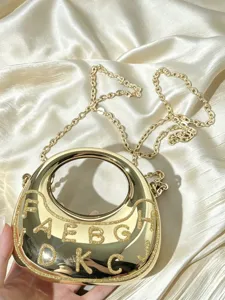 Goldene metallische Crescent Schultertasche mit rundem Griff und glitzernden Buchstaben.