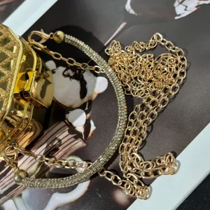 Exquisites Detail einer goldenen Abendtasche mit Strassbesatz und Metallkette.