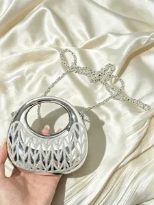 Silberne metallische Abendtasche Detail mit filigranem Gittermuster und rundem Henkel.