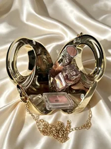 Nahaufnahme der luxuriösen goldenen Metallring-Abendtasche mit Kosmetikartikeln im Inneren.