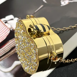 Goldene herzförmige Strass-Abendtasche mit Kettriemen und süßem Bienen-Verschluss Detail.