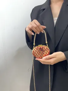 Nahaufnahme der eleganten Abendtasche mit rotem Gittermuster und funkelndem Strassgriff.