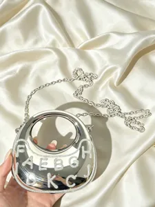 Silberne metallicfarbene Mondsichel-Umhängetasche mit Kette und glitzernden Buchstaben.
