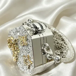 Stunning rhinestone crystal evening bag detail, sparkling metal minaudiere with gold charms.