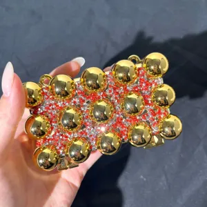 Acrylic evening rhinestone bag, detailed view showing gold spheres and red crystals.