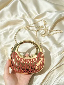 Goldene Abendtasche Detail mit glänzender Metalloberfläche, rotem Glitzer und Kette.