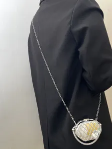 Detailansicht der schicken metallischen Abendtasche mit Kette, geometrischem Design und Steinen.