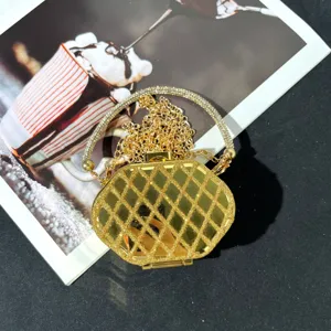 Detailaufnahme einer goldenen geometrischen Abendtasche mit Strass-Rundgriff und Kette.