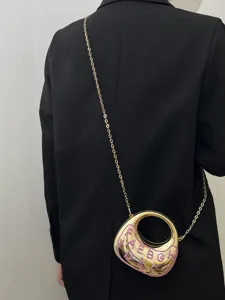 Detailaufnahme der goldenen metallic Halbmond Umhängetasche mit rosa Glitzer Text und Kette.