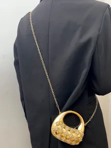 Detailaufnahme einer luxuriösen goldenen Acryl-Abendtasche mit funkelndem Kristall-Geflecht.