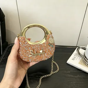 Nahaufnahme der glitzernden Abendtasche mit goldenem runden Ringgriff und Kettengurt.