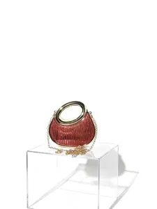 Nahaufnahme der glitzernden roten Abendtasche mit edlem Goldring-Griff und feiner Kette.