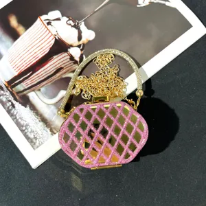 Detailaufnahme einer glitzernden Abendtasche in Rosa und Gold mit Strass-Kreisgriff.