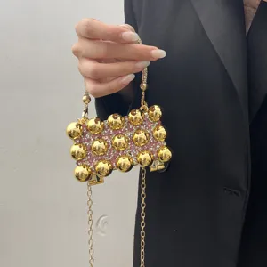 Acrylic rhinestone evening bag detail, sparkling gold balls and chain strap design for women.