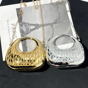Glänzende metallische Halbmond Handtasche Detailansicht mit elegantem Kettengürtel und hartem Etui.