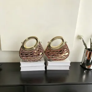 Detailaufnahme der eleganten goldenen Acryl-Strass-Abendtasche mit runden Griffen.