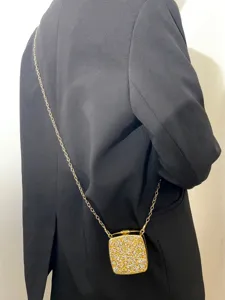 Detailansicht einer goldenen Acryl Abendtasche mit Strass und Kette für elegante Outfits.