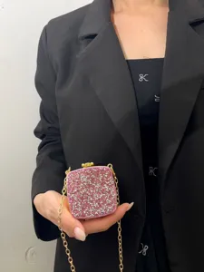 Detailaufnahme der rosa Strass-Abendtasche mit goldener Kette, elegant in der Hand gehalten.