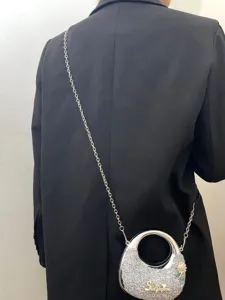 Nahaufnahme einer eleganten silbernen Strass-Ring-Umhaengetasche mit Kette und Text.