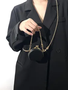 Close-up van een stijlvolle mini zwarte PU lederen knipbeurs portemonnee met gouden kralenketting.