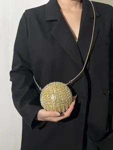 Close-up detail of luxury gold rhinestone spherical evening bag with chic metal chain strap.