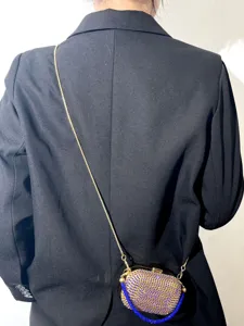 Detailansicht einer stilvollen Strass-Umhängetasche mit goldener Kette und blauen Steinen.