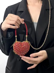 Detailansicht der roten Strass-Herz-Clutch mit goldener Kette, luxuriöse Abendtasche elegant.