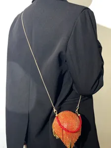 Vue détaillée d'un sac de soirée rond en strass étincelant avec franges et fine chaîne.