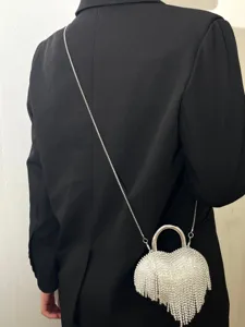 Gros plan sur le sac de soirée étincelant en forme de cœur avec franges et poignée métal.