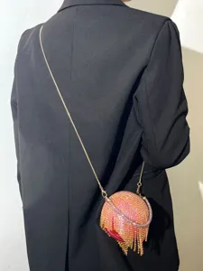 Vue détaillée d'un sac de soirée sphérique en strass étincelant avec de charmants pompons.