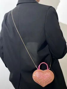 Vista dettagliata di una borsa a cuore rosa scintillante con strass e catena chic.