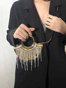 Nahaufnahme einer eleganten goldenen Abendtasche mit Ringgriff und funkelnden Strassfransen.