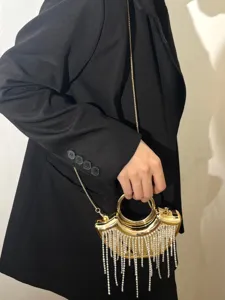 Exquisites Detail einer goldenen Abendtasche mit funkelnden Strassfransen und Ringgriff.