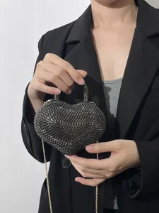 Dettaglio della borsa da sera a forma di cuore con strass brillanti e manico in metallo.