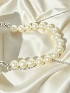 Dettaglio della tracolla per borsa di perle con perle bianche e catenina in metallo.