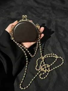 Detailopname van de compacte ronde PU-lederen tas met gouden ketting en stijlvolle sluiting.