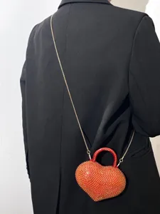 Primo piano della borsa da sera a forma di cuore con strass indossata con blazer nero.