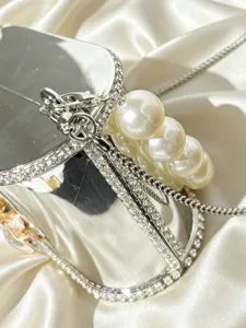 Primo piano delle scintillanti decorazioni in strass e del manico di perle sulla borsa da sera.